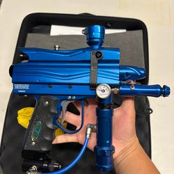 blue custom-milled Worr game product(WGP) Autococker-style paintball marker features an aftermarket vertical feedneck, an Empire pneumatic ram, and a WGP-style frame.