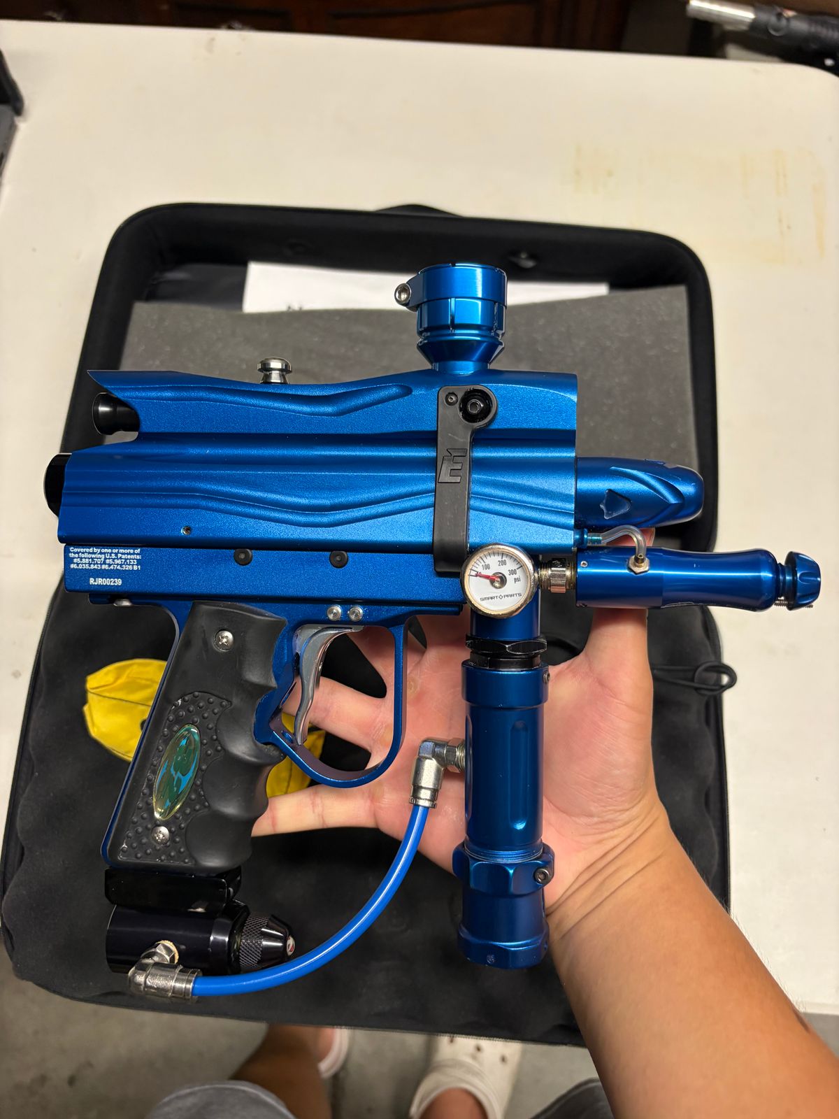 blue custom-milled Worr game product(WGP) Autococker-style paintball marker features an aftermarket vertical feedneck, an Empire pneumatic ram, and a WGP-style frame.